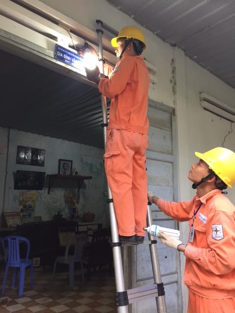 Công nhân Điện lực Côn Đảo thay bóng đèn tiết kiệm điện tại nhà dân. Ảnh: Mai Phương/BNEWS/TTXVN